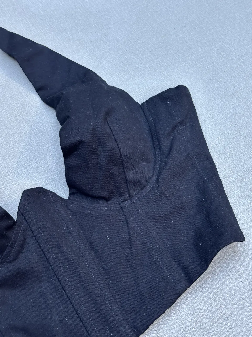 Top negro estilo corsé con tiras para atar en el cuello y espalda. Diseño moderno y sensual, ideal para looks de noche o para darle un toque audaz a tu outfit.