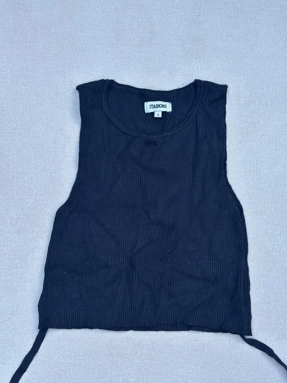 Musculosa negra de morley, con tiras para atar en la cintura. Ideal para un look casual y moderno.