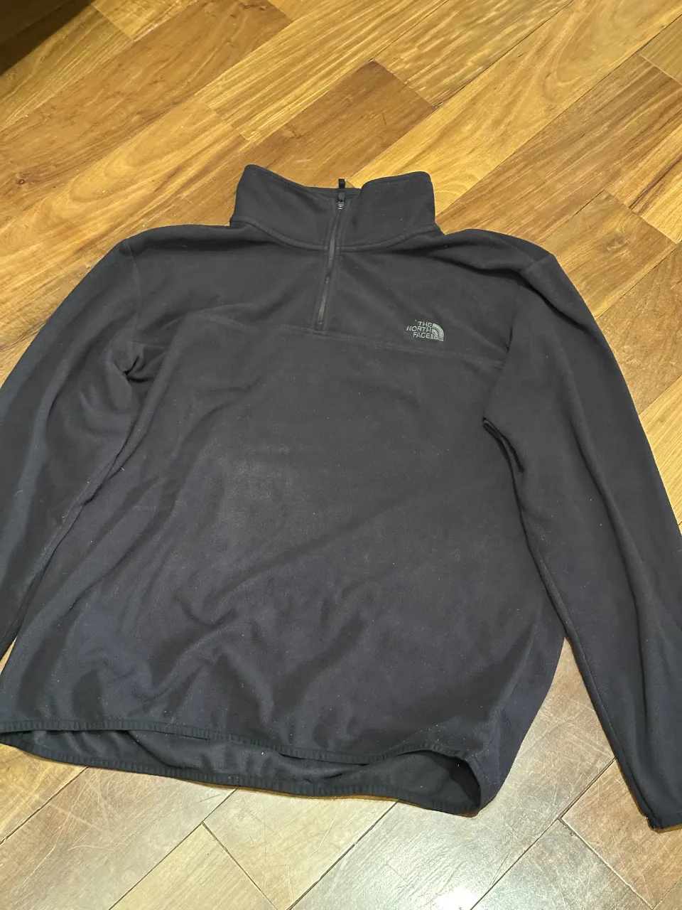 Buzo de friza negro con cuello alto y cierre de 1/4. Logo de la marca bordado en el frente.