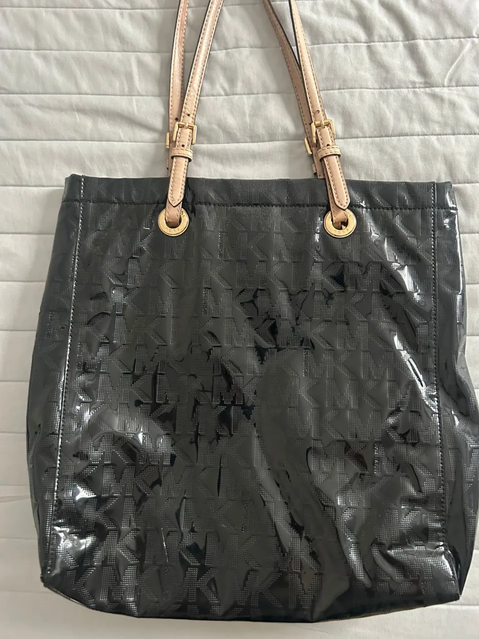 Bolso tote Michael Kors negro con monograma MK. Ideal para el día a día, tiene correas de cuero color natural y herrajes dorados. Un clásico que no puede faltar en tu guardarropa.