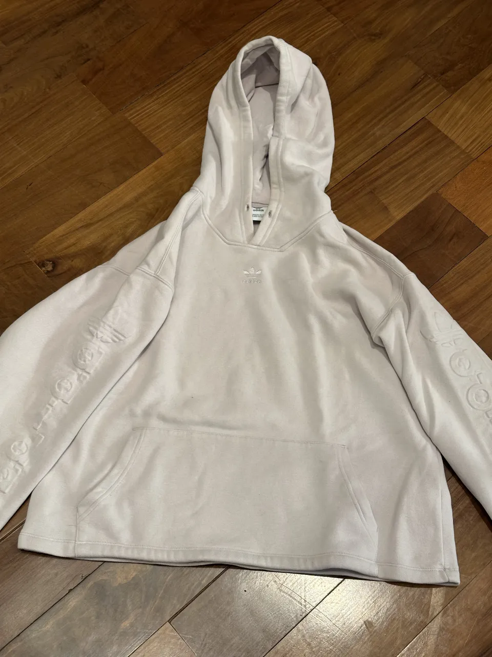 Buzo con capucha y bolsillo canguro. ℹ️ Tiene una mancha detras. Logo de Adidas en relieve en el frente y en las mangas. Es lila claro. 