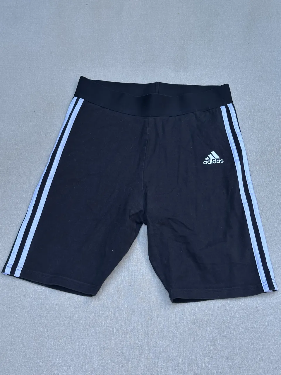 Shorts de algodón negros con las icónicas tres tiras blancas de Adidas a los costados. Perfectos para entrenar o para un look deportivo casual.