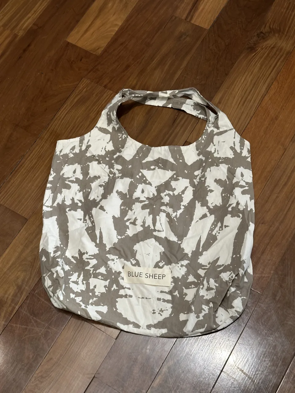 Bolsa de tela con estampa abstracta en tonos blanco y gris. Posee dos asas cortas.