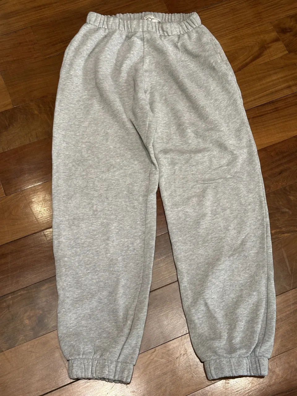 Pantalón de algodón gris con cintura elastizada y puños en los tobillos. Presenta un pequeño detalle de rotura en la parte trasera.