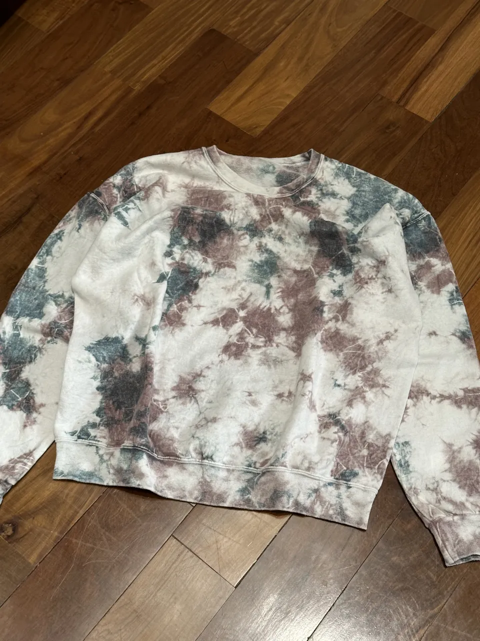 Buzo de cuello redondo con estampa tie-dye en tonos blancos, marrones y verdes.