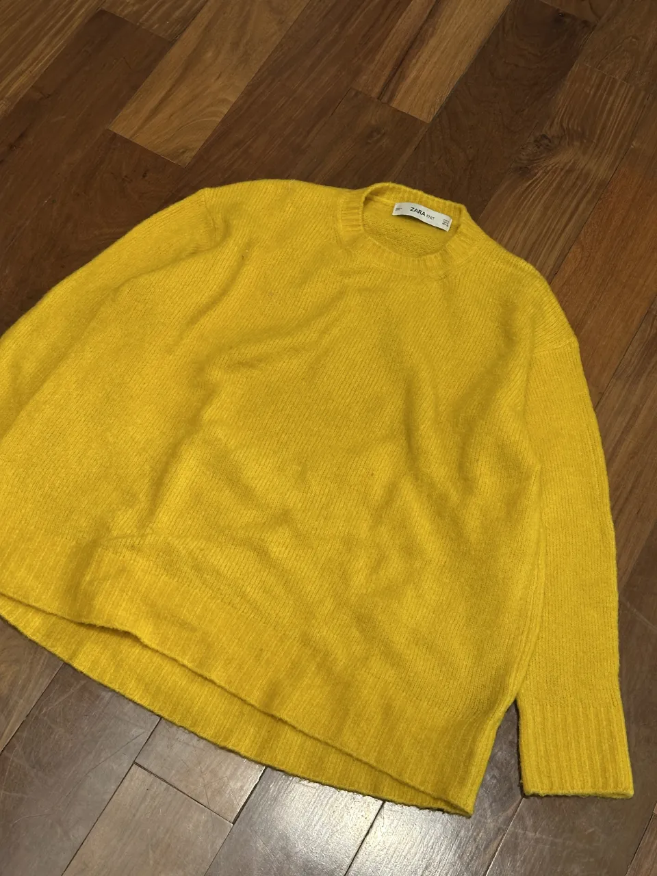 Sweater amarillo de manga larga con cuello redondo. Tiene una pequeña mancha en el frente.