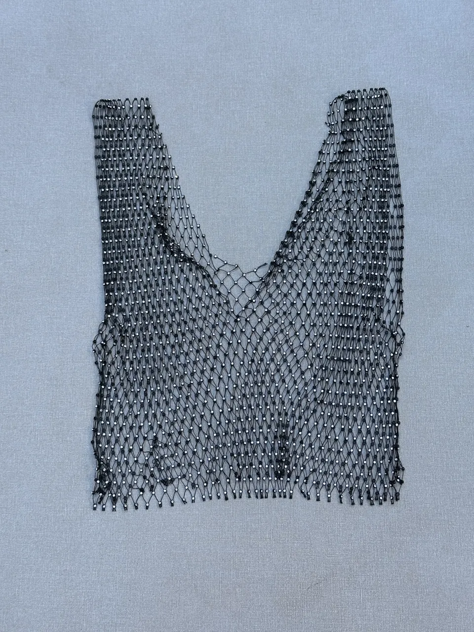 Top de red negro con brillos, ideal para looks audaces y modernos. Perfecto para combinar con otras prendas y crear outfits únicos.