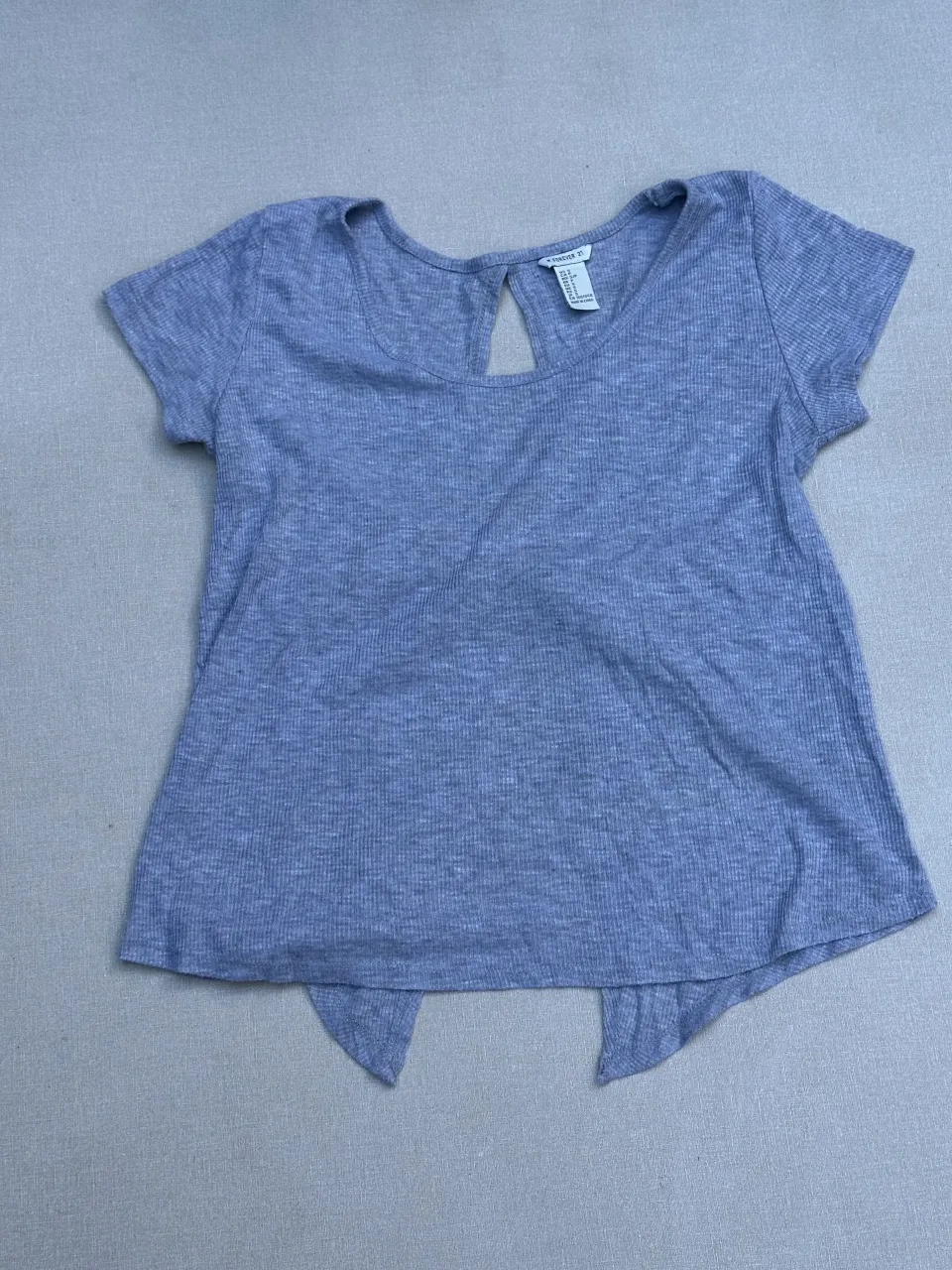 Remera gris de algodón con mangas cortas y un diseño abierto en la espalda con un nudo.