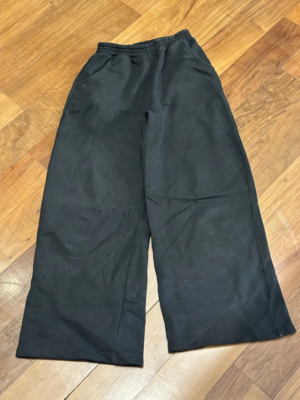 Pantalón negro de tela con cintura elastizada y bolsillos laterales.