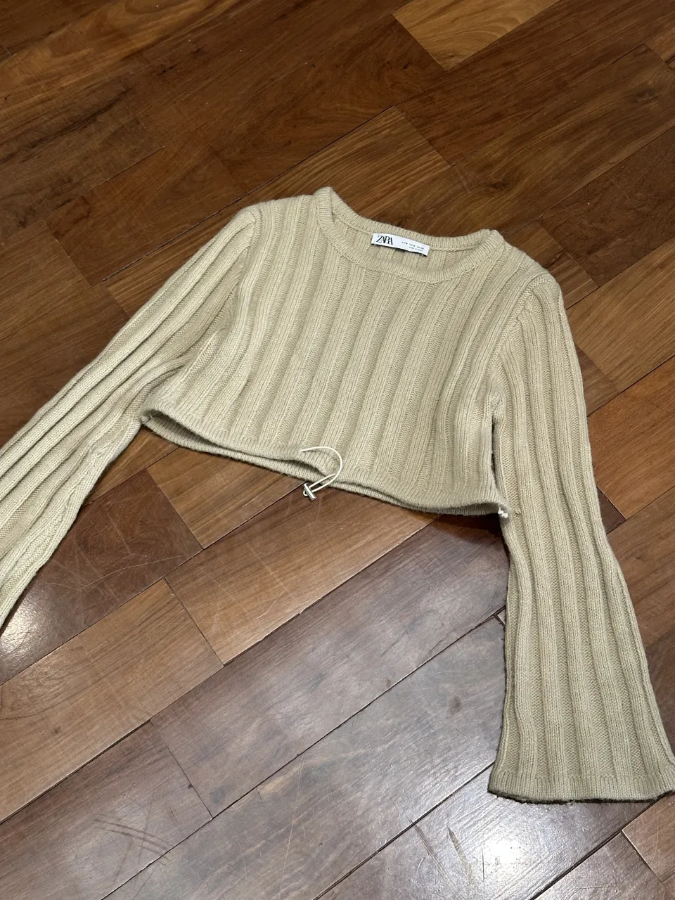 Sweater crop de tejido de punto con cordón ajustable en la cintura. Mangas largas acampanadas.