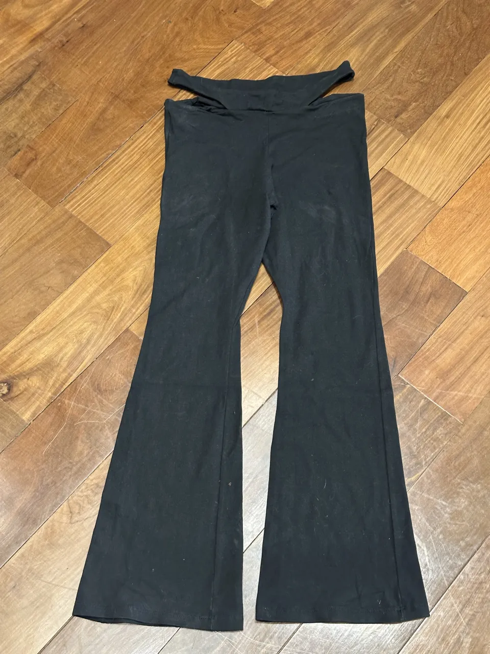 Pantalón negro con recortes en la cintura y corte acampanado en la parte inferior.