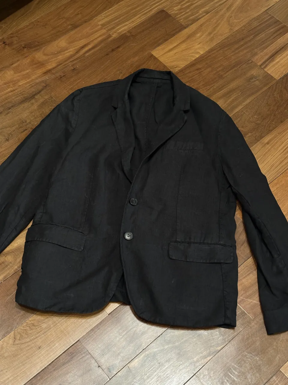 Blazer negro de lino con dos botones al frente y bolsillos con solapa.