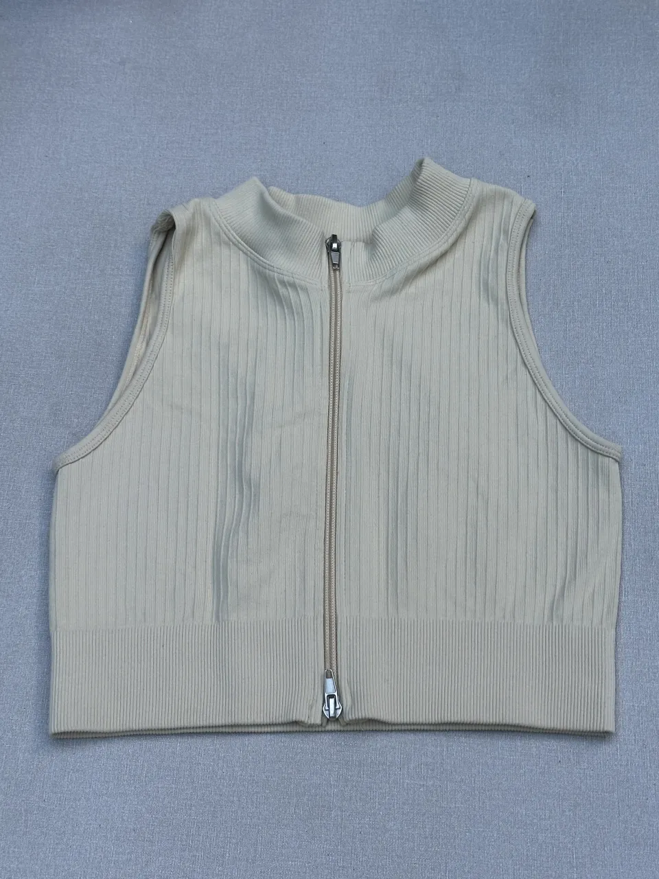 Top deportivo de cuello alto con cierre al frente. Diseño acanalado y moderno, ideal para entrenamientos o para un look casual y canchero. La marca MIOFAR se encuentra estampada en la parte inferior.