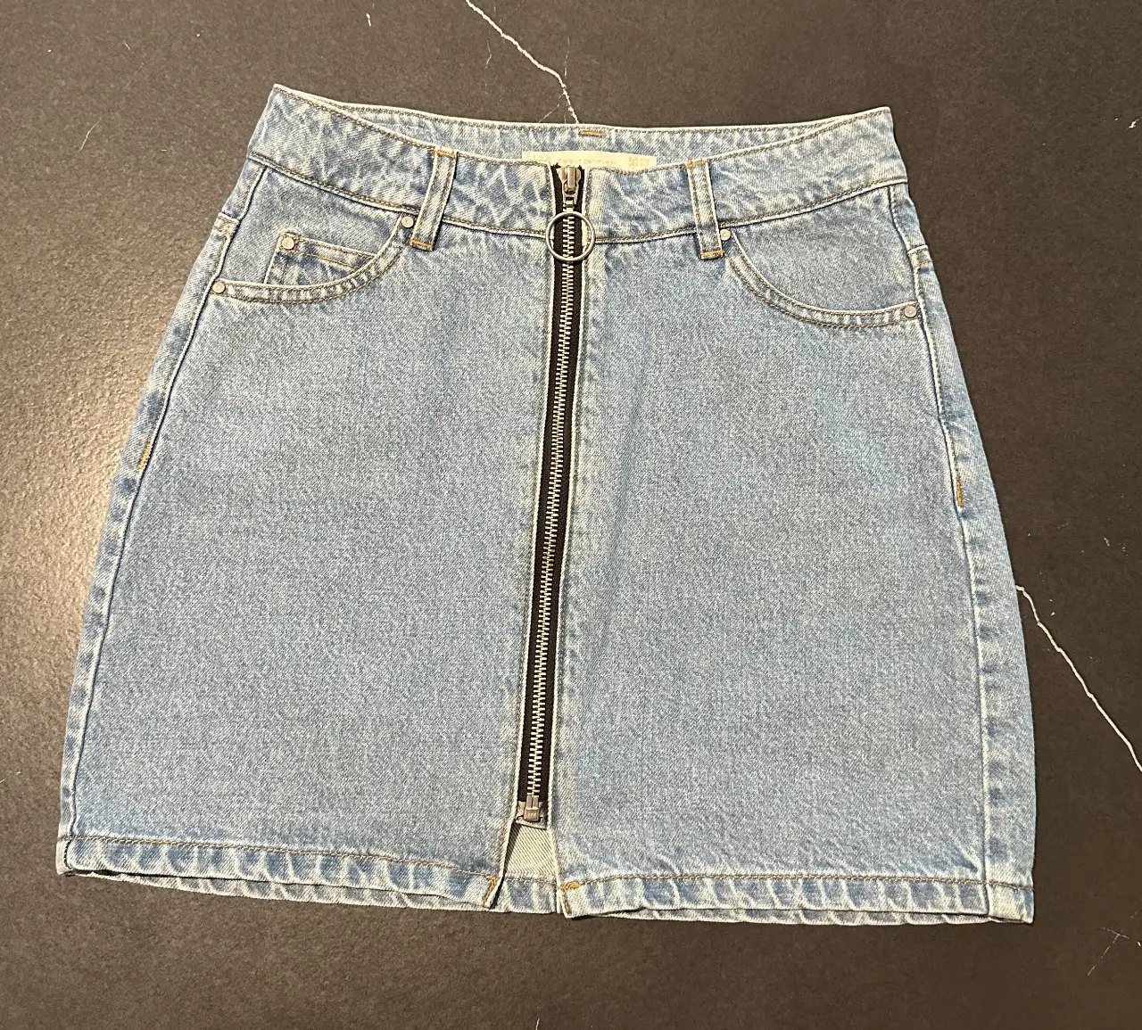 Minifalda de jean azul claro con cierre frontal. Un clásico para un look casual y versátil.