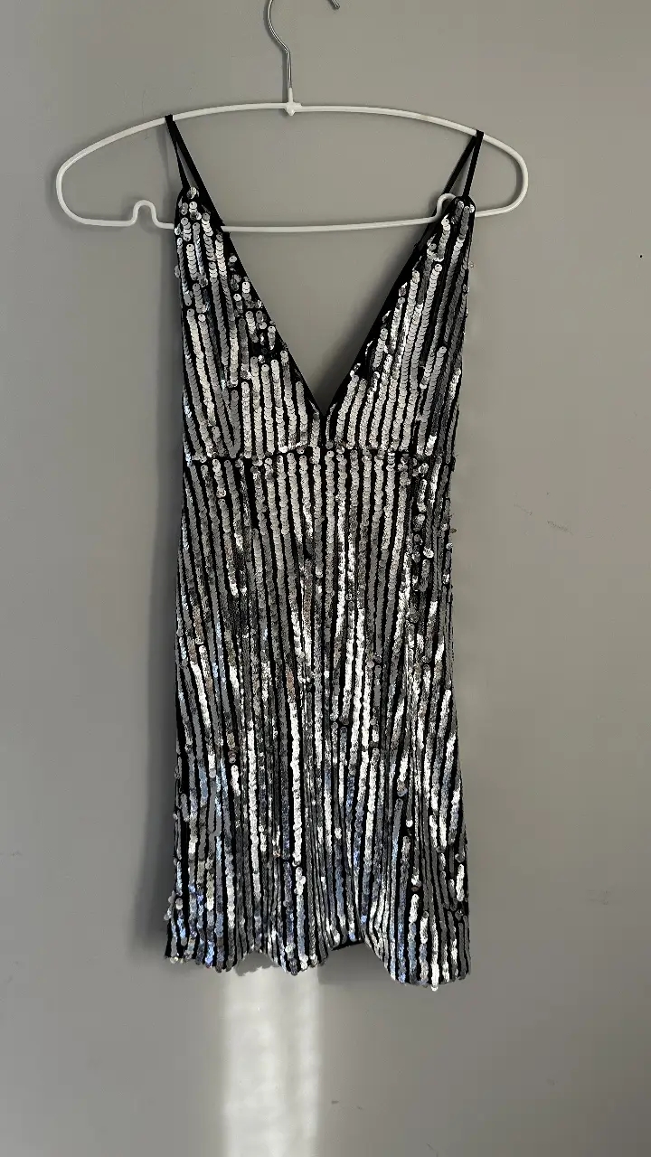 Vestido mini de fiesta con lentejuelas plateadas y espalda descubierta. En la espalda los breteles se cruzan, por eso se ve asi en la foto de atras. Ideal para eventos especiales y salidas nocturnas.