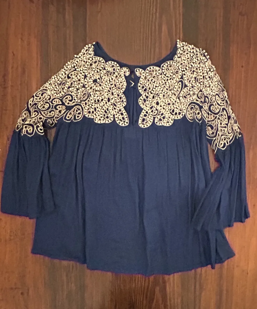 Blusa azul con detalles bordados con perlas en la parte superior y mangas acampanadas. Ideal para un look bohemio y elegante.