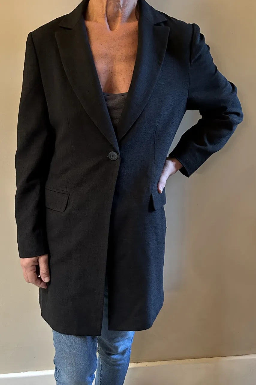 Blazer largo negro, ideal para un look elegante y sofisticado. Perfecto para combinar con jeans o pantalones de vestir.