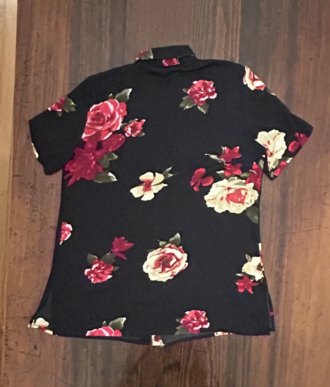 Camisa de manga corta para mujer, con estampado floral en tonos rojos y blancos sobre fondo negro. Ideal para un look casual y con estilo.