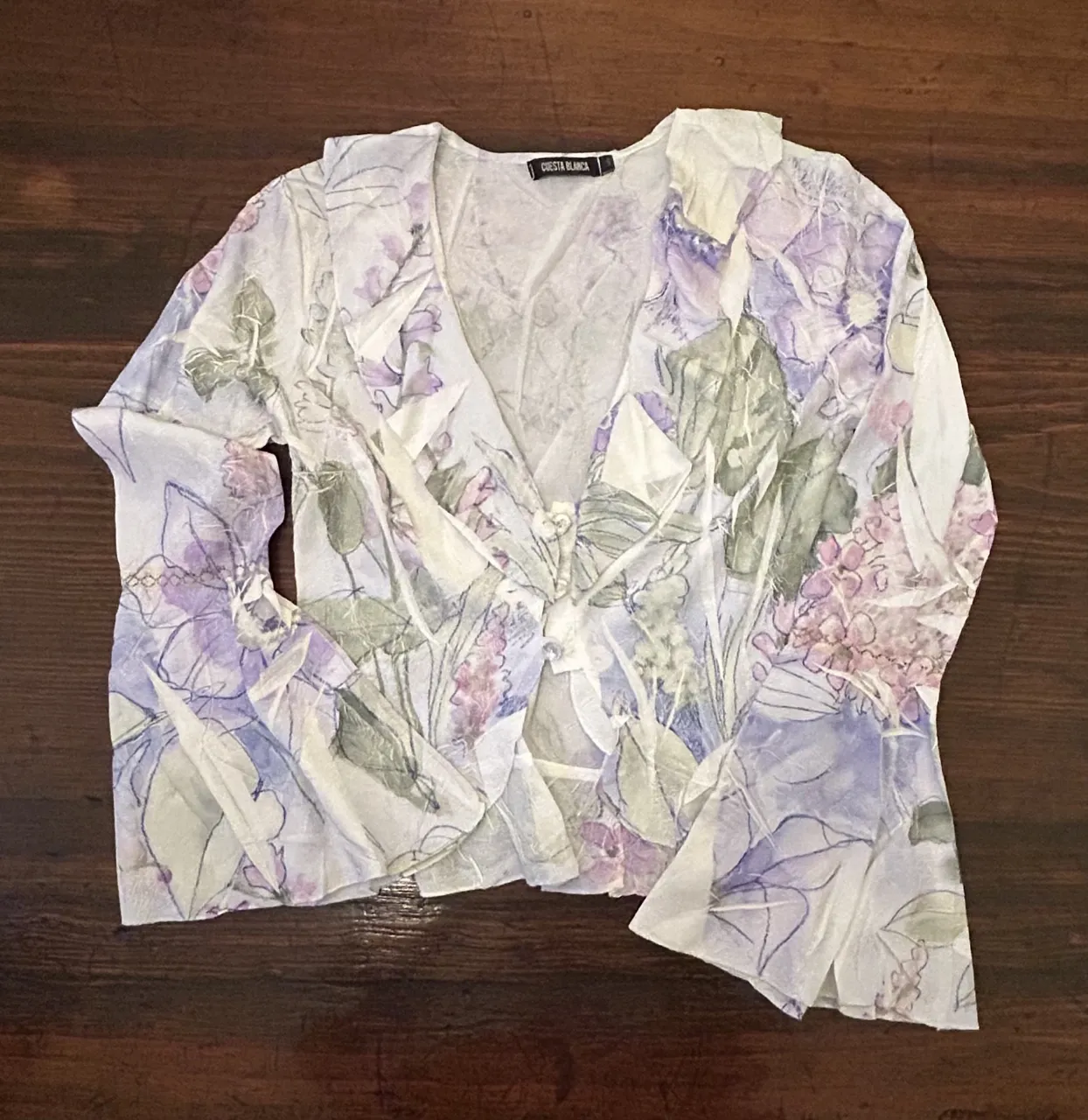 Blusa de mujer con estampado floral en tonos lilas y verdes. Diseño con escote en V y mangas amplias. Ideal para un look fresco y primaveral.