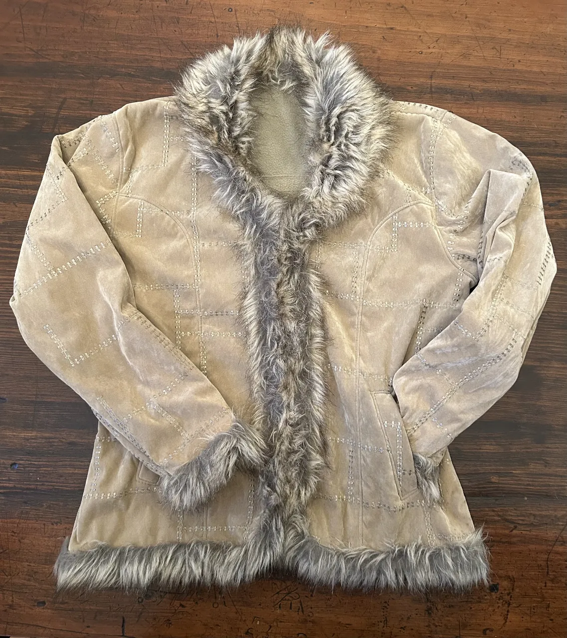 Campera de gamuza con detalles de piel en cuello, borde y puños. Diseño con costuras decorativas y bolsillos.