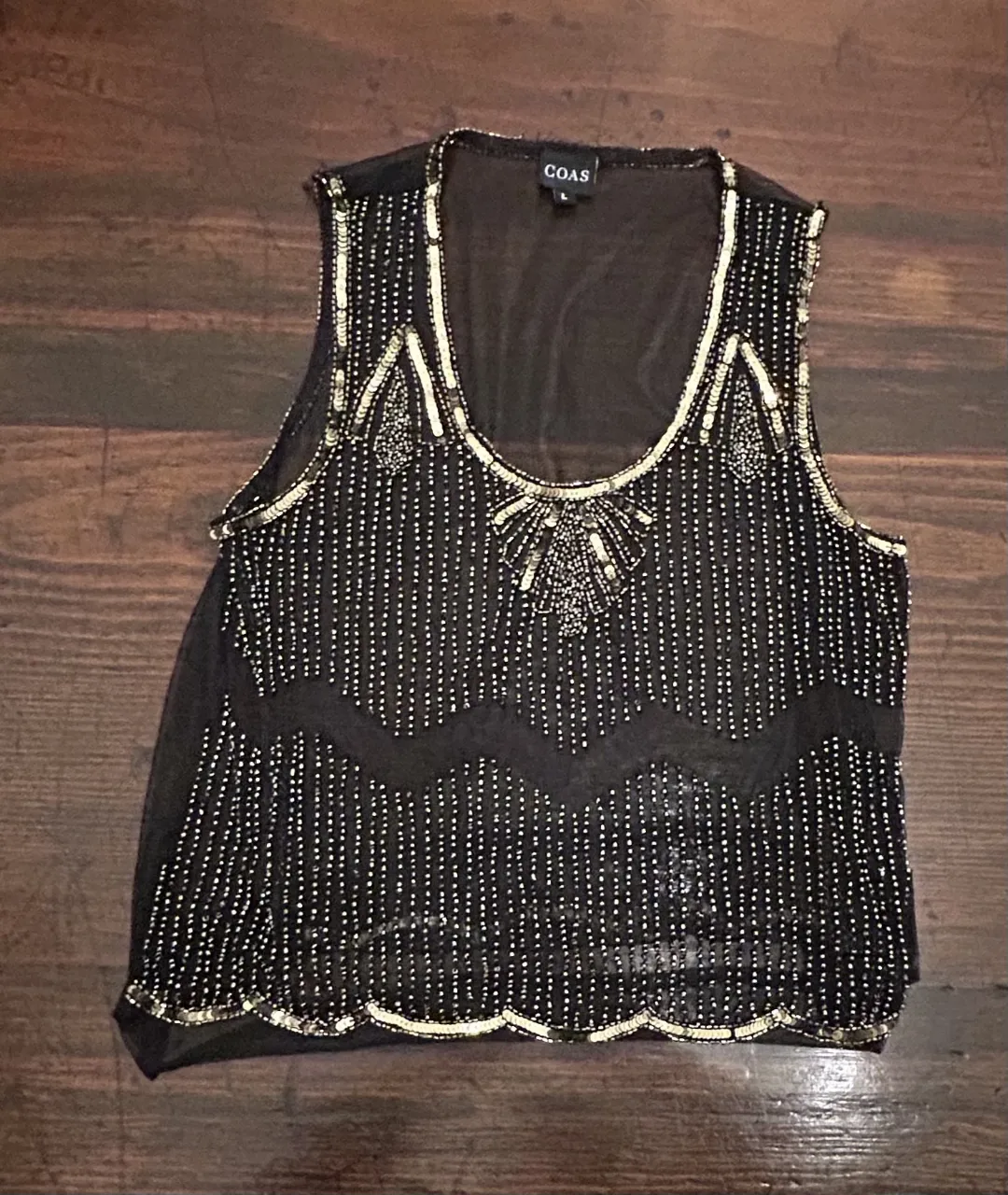 Musculosa negro con detalles dorados, ideal para fiestas y eventos especiales. Diseño elegante y sofisticado.