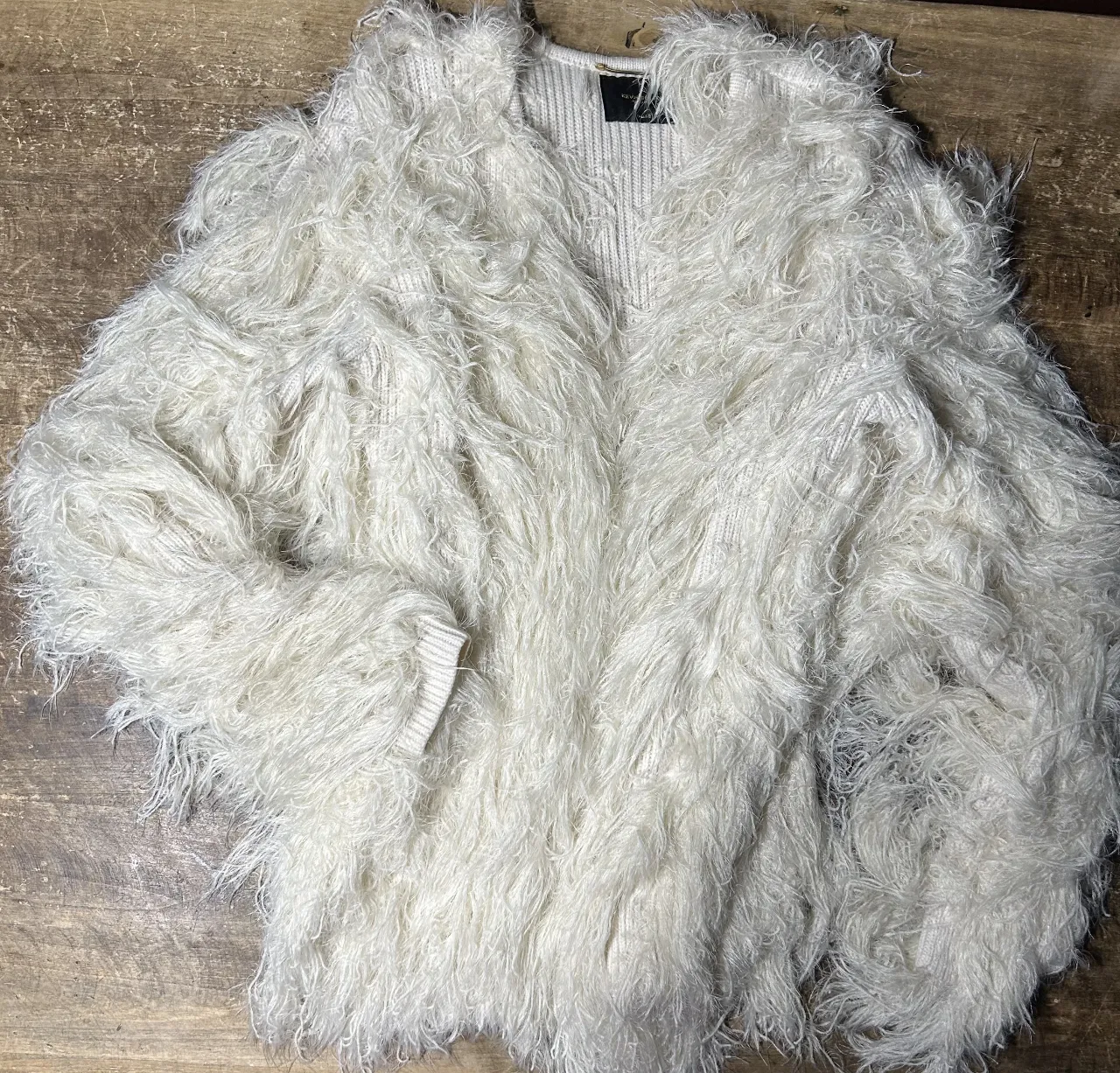 Cardigan blanco con textura de pelo largo, ideal para un look moderno y abrigado. Perfecto para combinar con diferentes outfits.