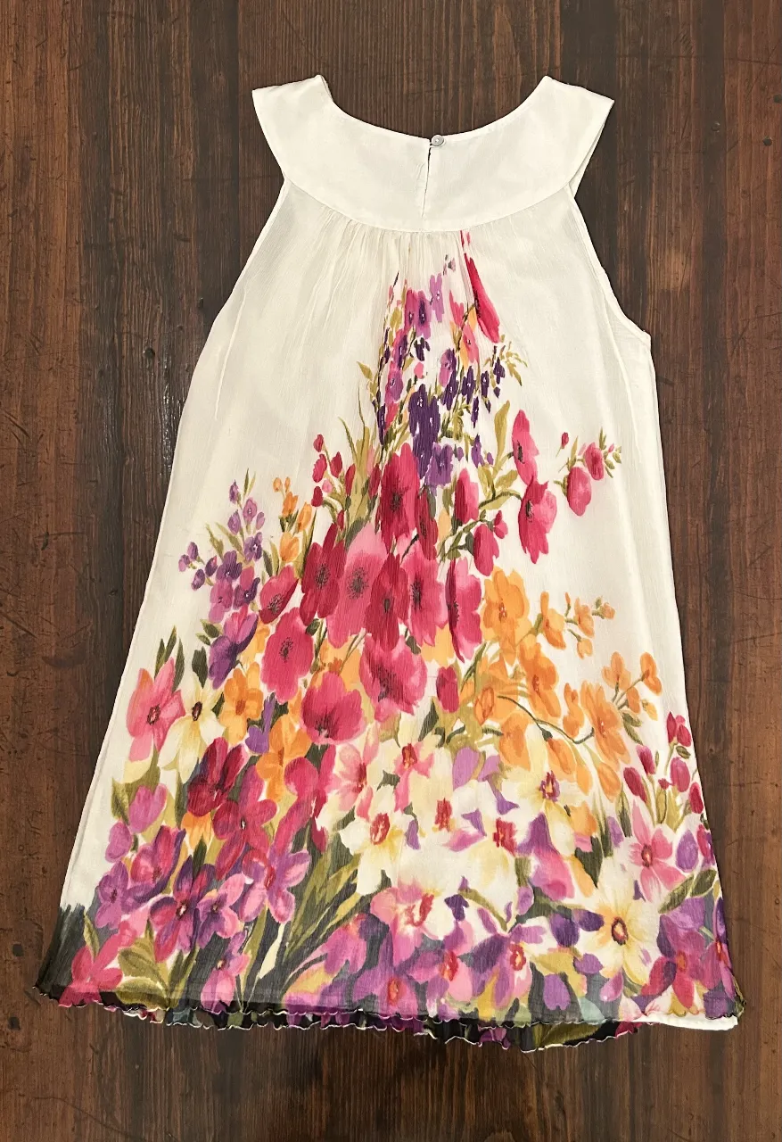 Vestido mini blanco con estampado floral en tonos rosas, morados y naranjas. Ideal para un look fresco y femenino.
