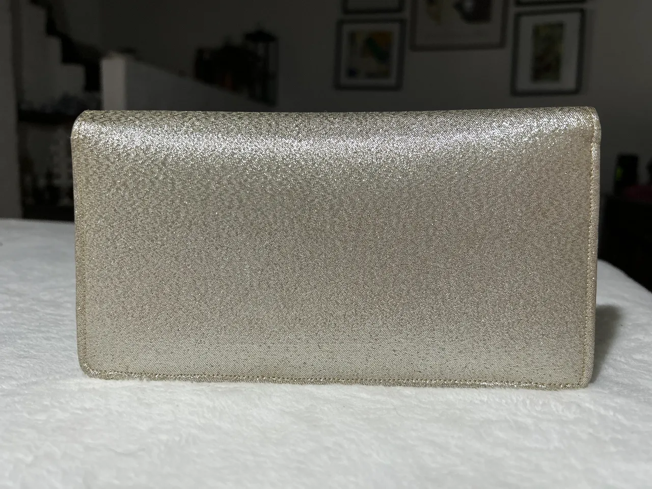 Clutch de mano plateada con textura brillante, ideal para eventos especiales. Diseño elegante y sofisticado.