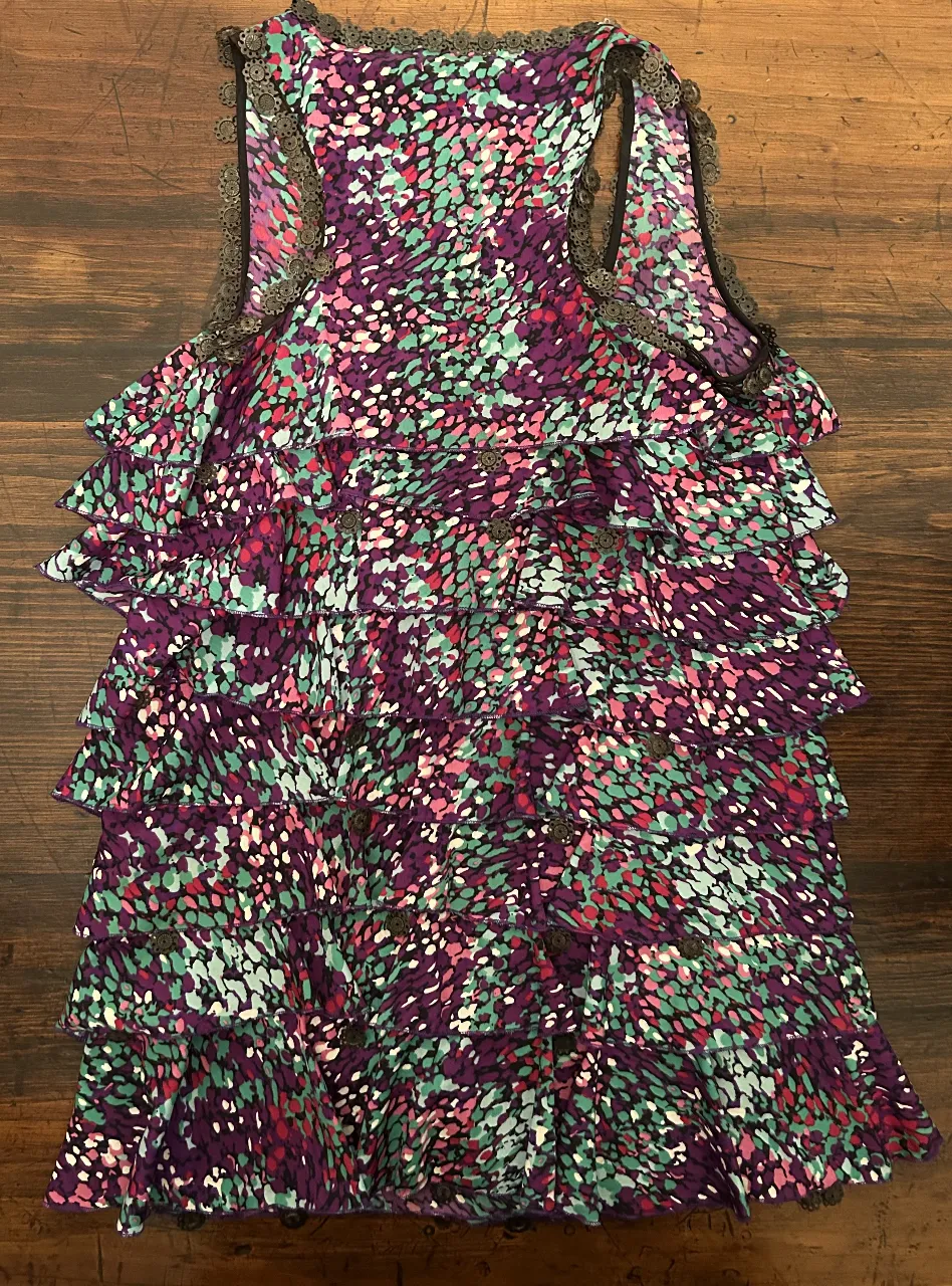 Vestido mini con estampado floral en tonos violetas, verdes y rosas. Diseño con volados. Ideal para un look fresco y femenino.