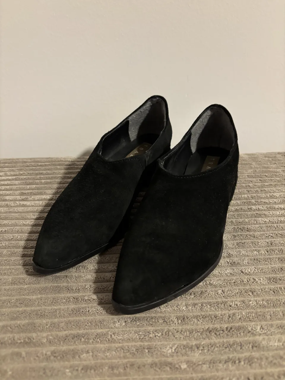 Zapatos negros de gamuza, estilo mocasín con punta fina y taco bajo. 