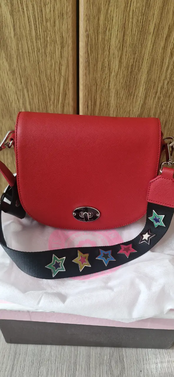 Bandolera roja con correa negra adornada con estrellas de colores. Ideal para un look casual y moderno.