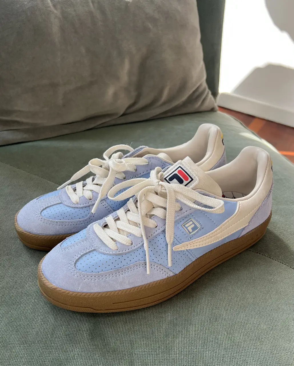 Zapatillas Fila modelo retro en color celeste y blanco. Con logo de la marca en la lengüeta y en el lateral. Suela de goma marrón. tienen un solo uso.