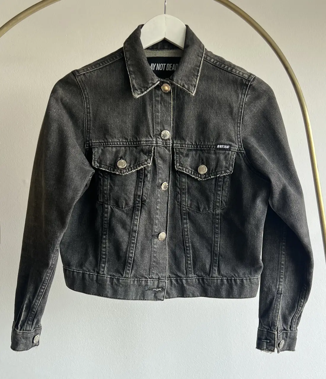 Campera de jean gris oscuro de la marca AY NOT DEAD. Corte clásico con botones metálicos y dos bolsillos delanteros. Ideal para un look casual y canchero.