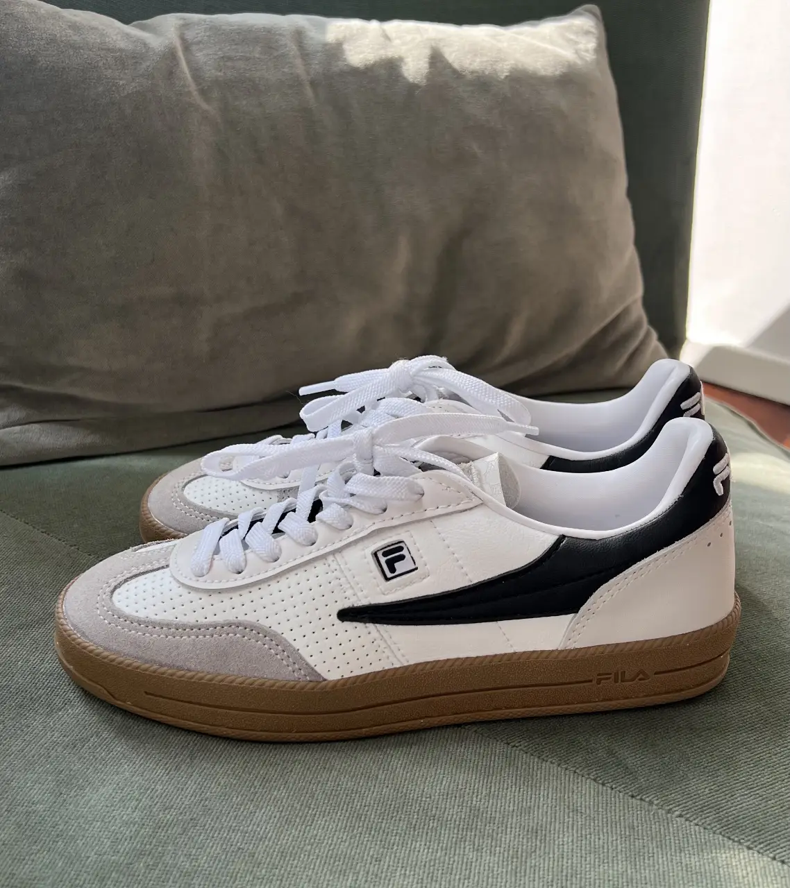 Zapatillas Fila blancas con detalles en negro y suela marrón. Diseño clásico y cómodo, ideales para uso diario. tienen un uso 