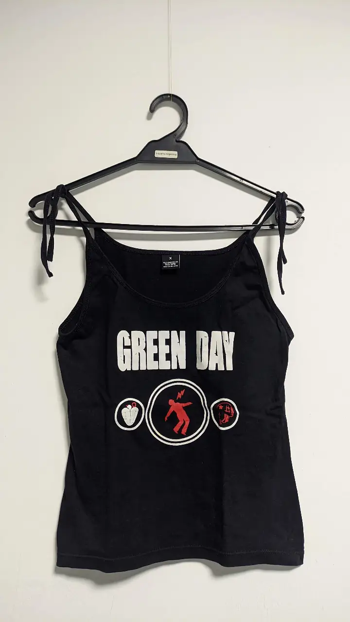 Musculosa de Green Day, negra con estampado del logo de la banda y sus símbolos característicos. Con breteles para atar (regulables). Ideal para un look rocker y casual.