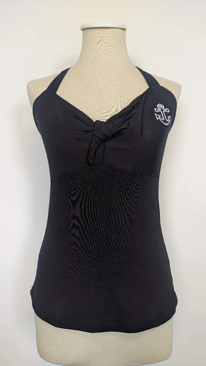 Top halter negro con detalle de moño en el frente y estampado de ancla blanca. Ideal para un look marinero y fresco.