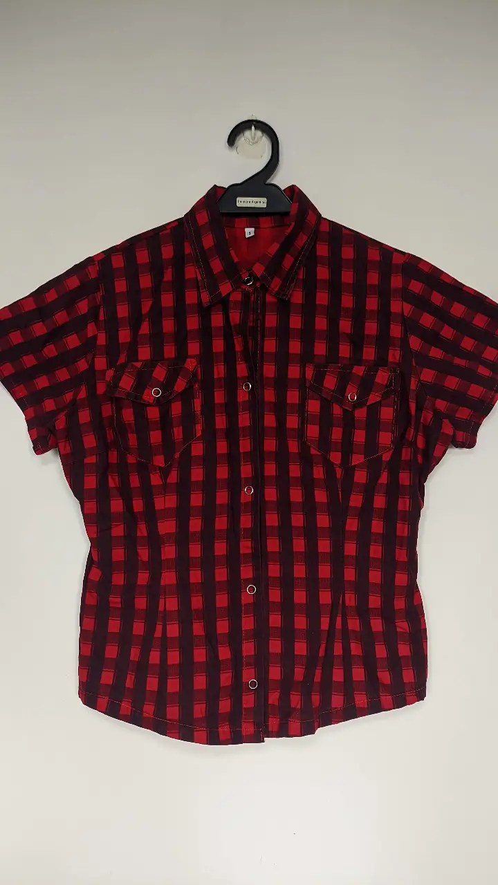Camisa a cuadros roja y negra, de manga corta, con dos bolsillos delanteros. Ideal para un look casual y canchero.