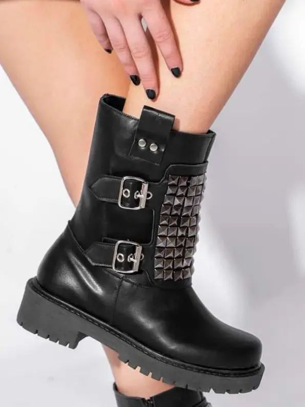 Botas negras de caña media de cuero ecológico con detalles de tachas plateadas y hebillas. Estilo rocker y moderno, ideales para un look audaz.