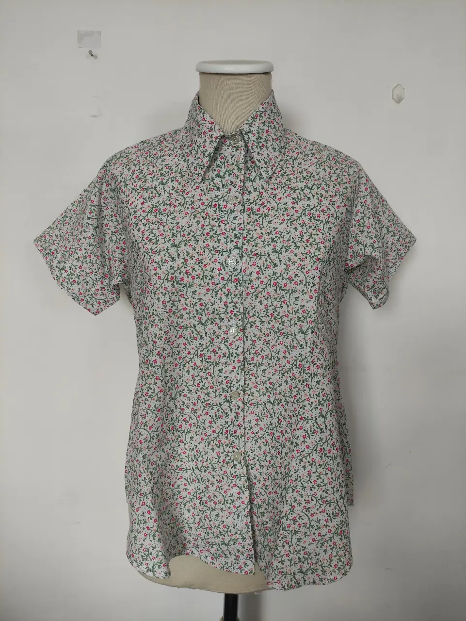 Camisa estampada con diseño floral en tonos rojos y verdes sobre fondo blanco. Ideal para un look fresco y casual.