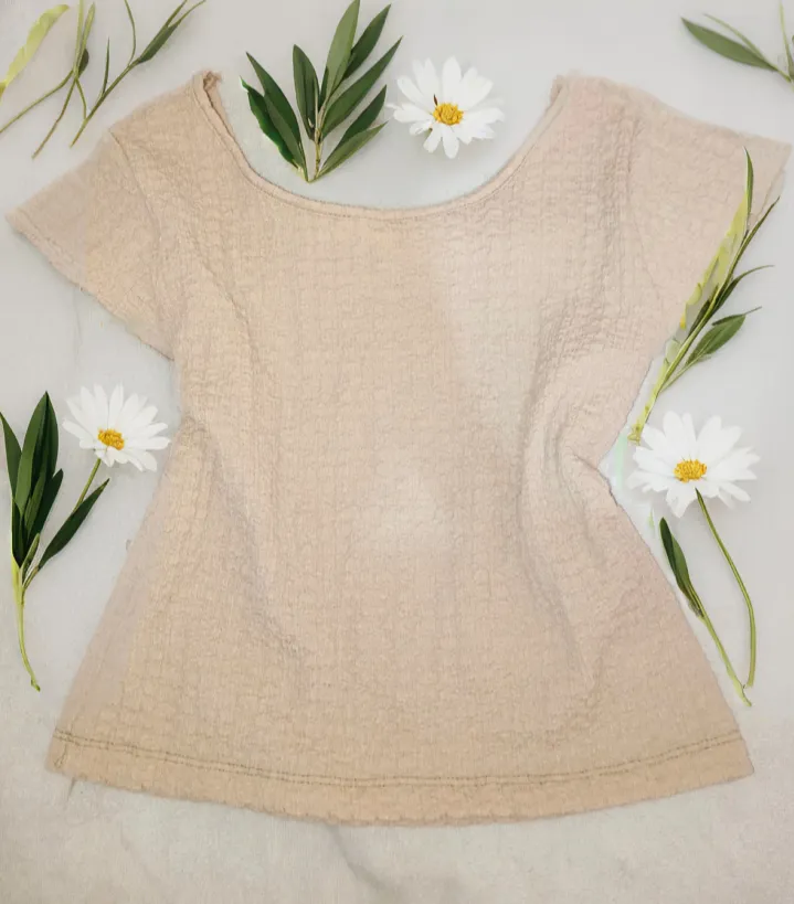 Remera de manga corta en color crudo, con una textura sutil y un corte holgado. Ideal para un look casual y cómodo.