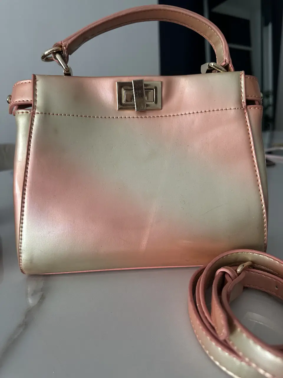 Cartera de mano con diseño degradado en tonos rosa y dorado. Ideal para un look elegante y moderno.