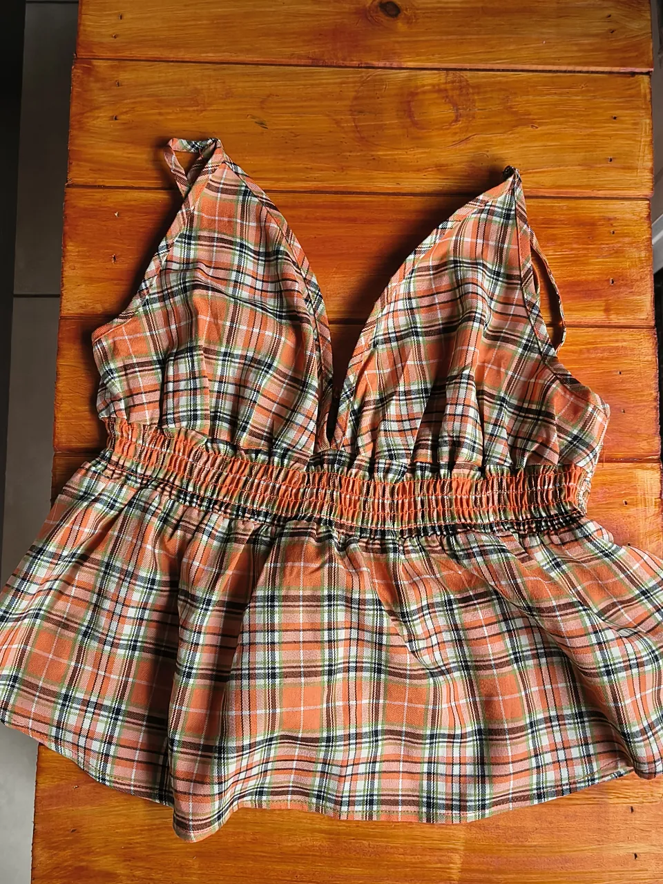 Top a cuadros naranja con escote en V y elástico en la cintura. Ideal para un look canchero y fresco. Talle M/L