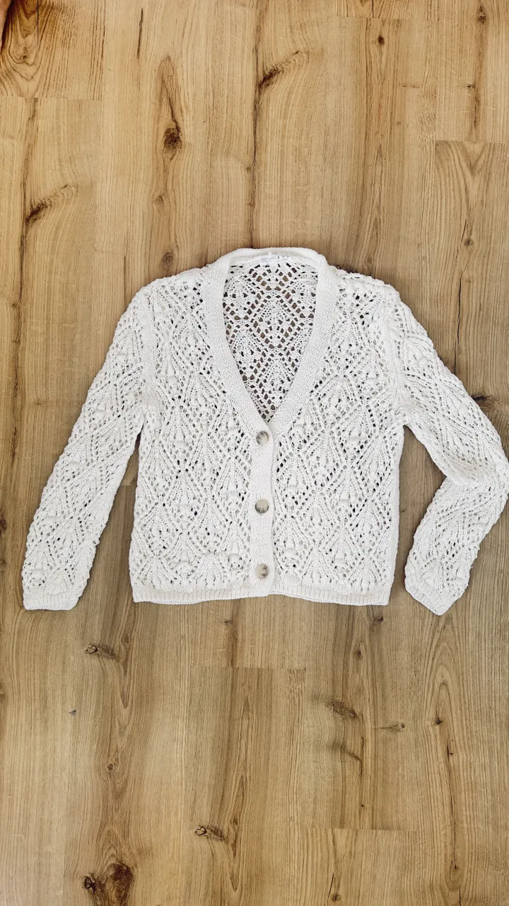 Cardigan tejido blanco, con botones y detalles de crochet. Ideal para un look delicado y fresco.