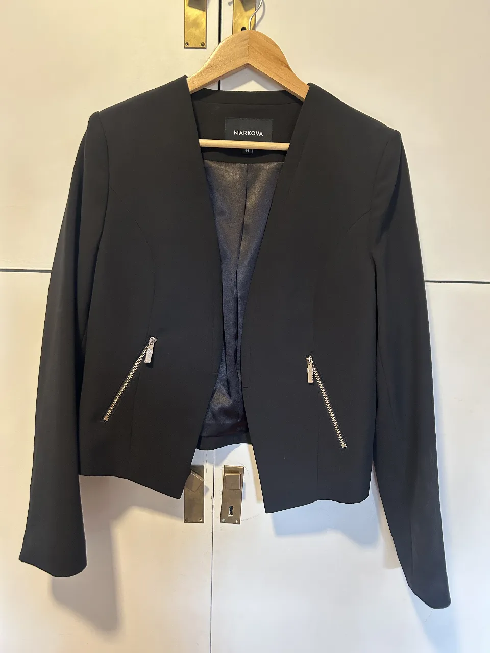 Elegante blazer negro de mujer, con cierre frontal y bolsillos con cremallera. Ideal para un look sofisticado y moderno. Perfecto para combinar con diferentes outfits.