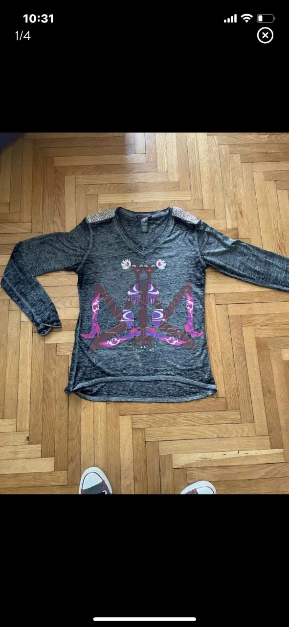 Remera de manga larga con diseño artístico y detalles en los hombros. Ideal para un look casual con un toque de originalidad.