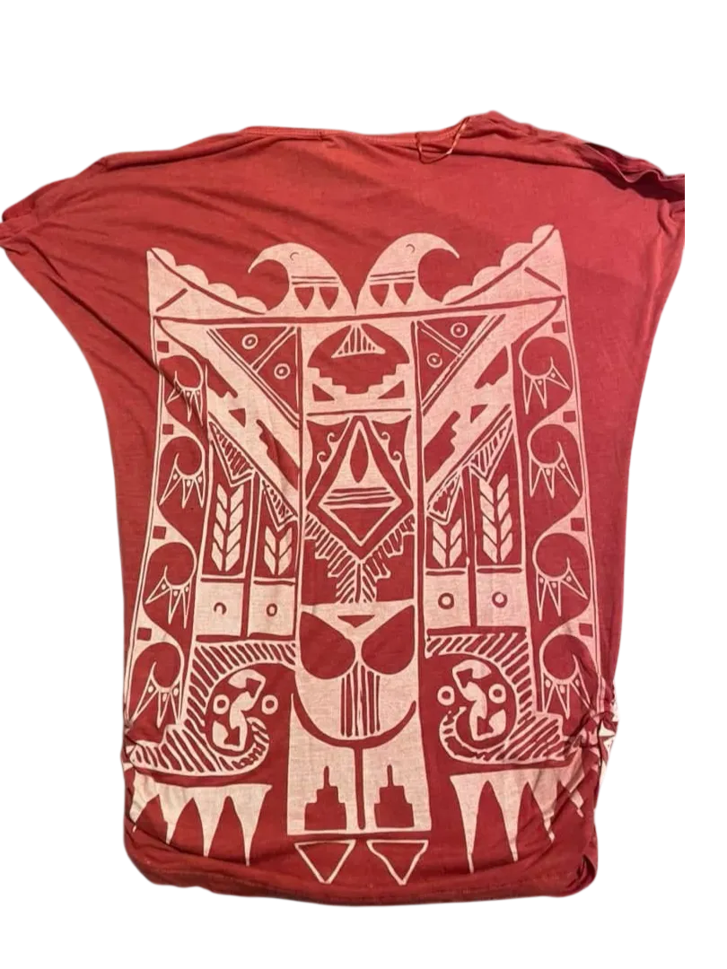 Remera de mujer con diseño tribal en color blanco sobre fondo rojo. Corte holgado y mangas amplias, ideal para un look casual y cómodo. Perfecta para combinar con jeans o shorts.