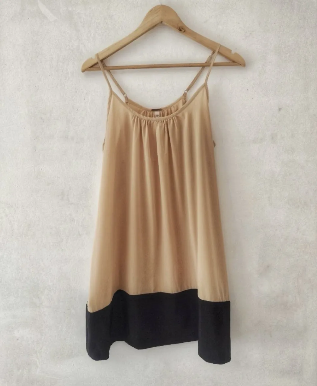 Vestido camisero súper fresco y liviano, ideal para los días de calor. Tiene un diseño bicolor con la parte superior en color tiza y la inferior en negro. Las tiras finas le dan un toque delicado. Perfecto para un look casual y chic.