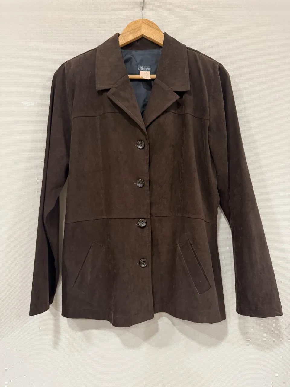 Chaqueta de gamuza marrón, con botones al frente y bolsillos. Ideal para un look elegante y casual.