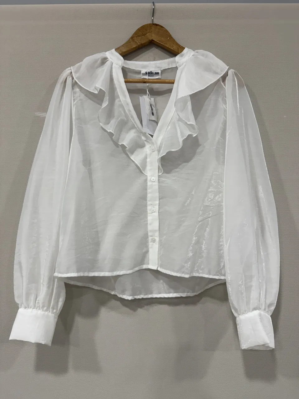 Blusa blanca de organza con volados en el cuello y mangas largas abullonadas. Un diseño delicado y romántico, perfecto para un look elegante.