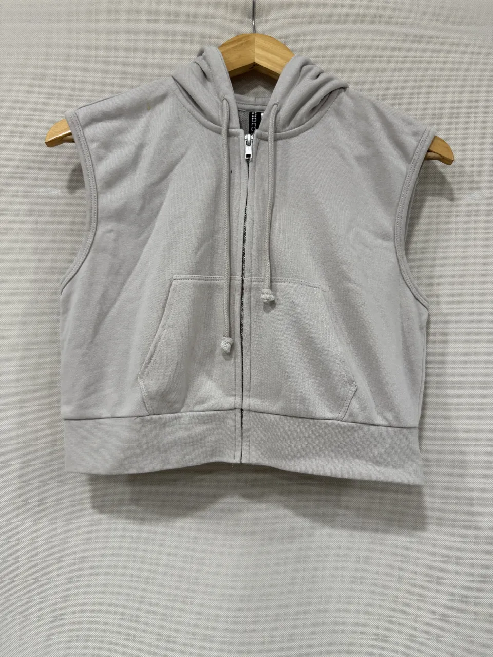 Buzo crop sin mangas con capucha y cierre completo. Posee bolsillo tipo canguro al frente. Ideal para un look casual y moderno.